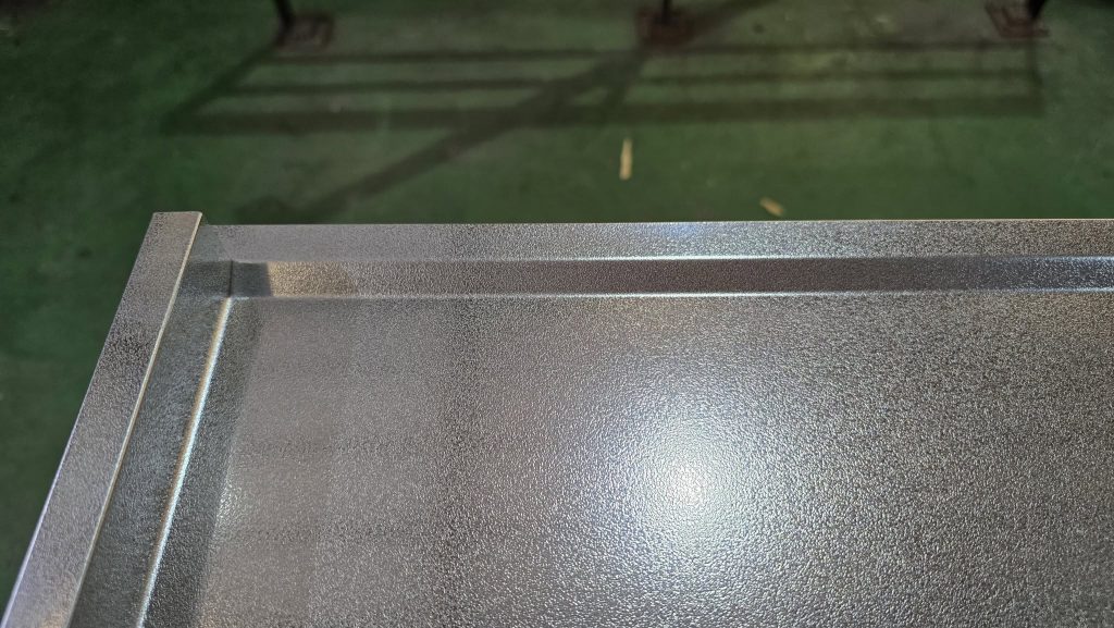 Cạnh ngoài của mặt bàn inox vân sần được chấn CNC gờ chắn nước khép kín, bảo vệ hệ tủ bên dưới luôn khô ráo.